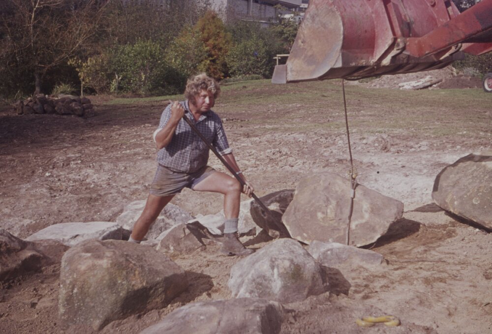 Groundsman assisting with landscaping large rocks