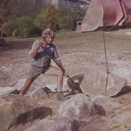 Groundsman assisting with landscaping large rocks