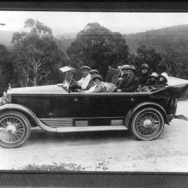 Nine people seated in early model car.