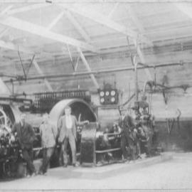 Men standing in factory room possibly paper mill