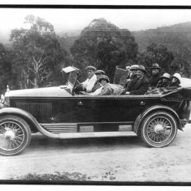 Nine people seated in early model car
